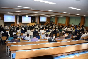 写真5　多数の学生が集まった講演会場の様子（挨拶は常任理事　高村先生）